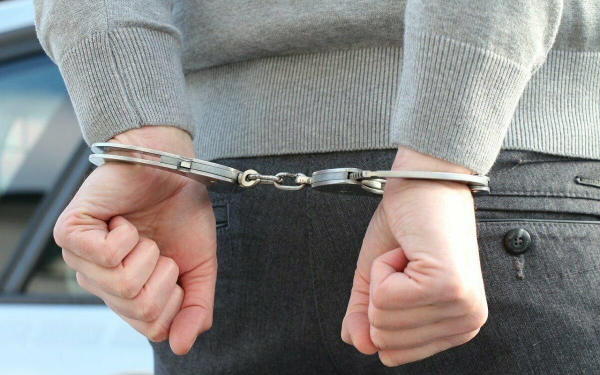 Hände mit Polizei-Handschellen nach einer Festnahme zusammengehalten Hände mit Polizei-Handschellen nach einer Festnahme zusammengehalten